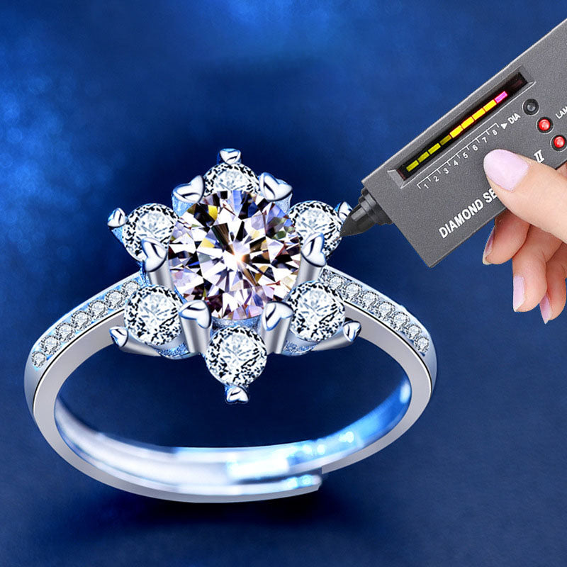 Diamond tester touching a snowflake moissanite ring with CZ accents and pavé band.