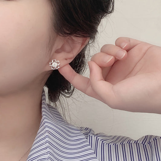 Woman wearing cherry-blossom moissanite stud earring in rhodium-plated 925 sterling silver.