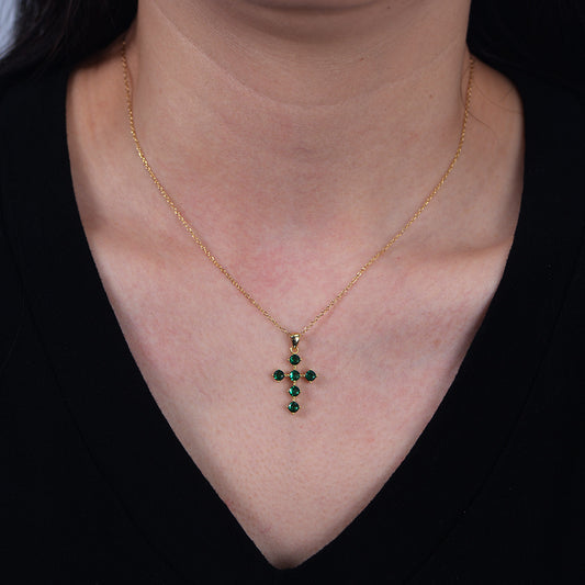 Model wearing gold green CZ cross pendant necklace at collarbone