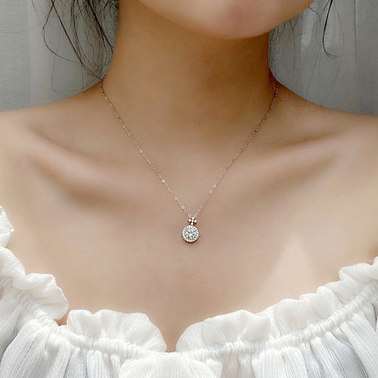 Model wearing a delicate moissanite halo pendant necklace on a silver chain with off-shoulder white top.
