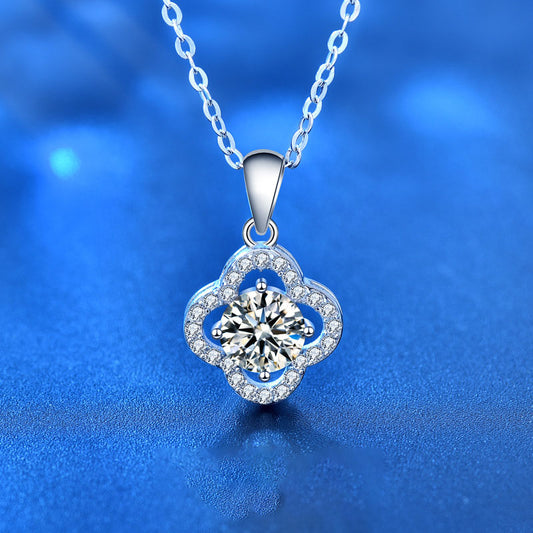 Close-up of sterling silver four-leaf clover moissanite pendant on blue background