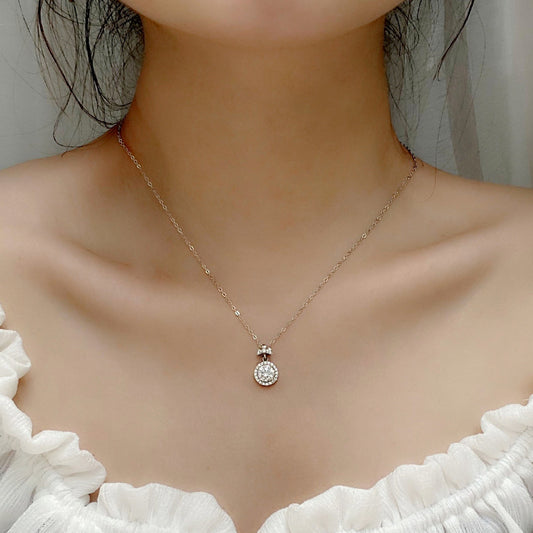 Woman wearing dainty sterling silver moissanite perfume bottle pendant necklace, styled with a soft neckline