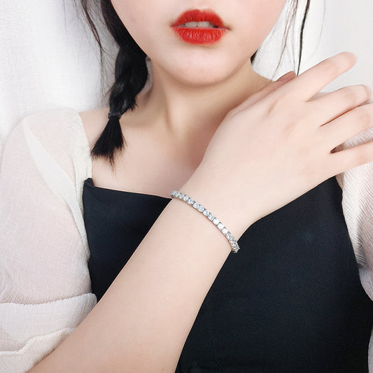 Woman modeling slim silver CZ tennis bracelet, elegant unisex sterling silver piece