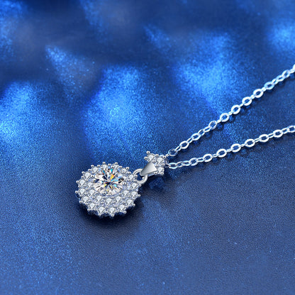 Flat lay of moissanite sunshine halo pendant necklace on shimmering blue surface.