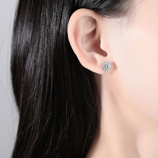 Round halo moissanite stud earring worn on ear for size reference.