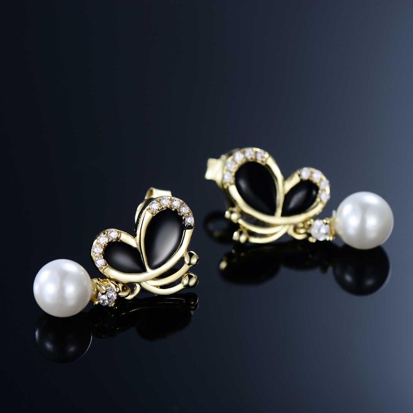 Black enamel butterfly pearl dangle earrings with CZ accents on a reflective black background.