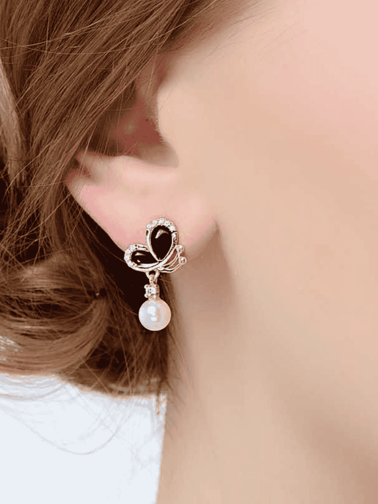 Close-up of model wearing black enamel butterfly pearl dangle earring in 18K gold-plated 925 silver with CZ accents