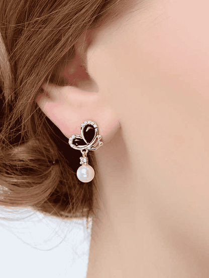 Close-up of model wearing black enamel butterfly pearl dangle earring in 18K gold-plated 925 silver with CZ accents