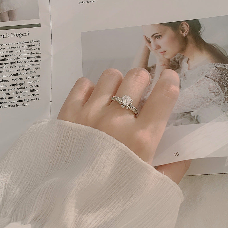 Lifestyle photo: floral halo moissanite ring on hand, showing sparkle and slim CZ pavé band.