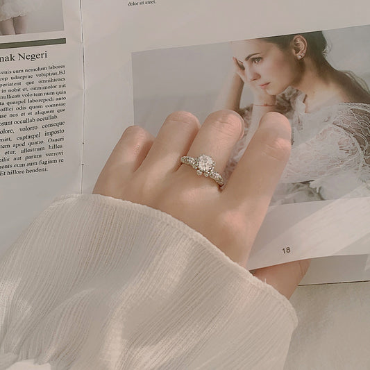 Lifestyle photo: floral halo moissanite ring on hand, showing sparkle and slim CZ pavé band.