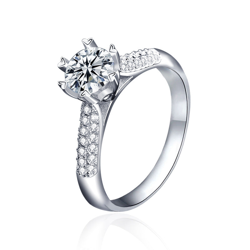 Studio packshot of six prong moissanite ring with pavé shoulders on a white background.