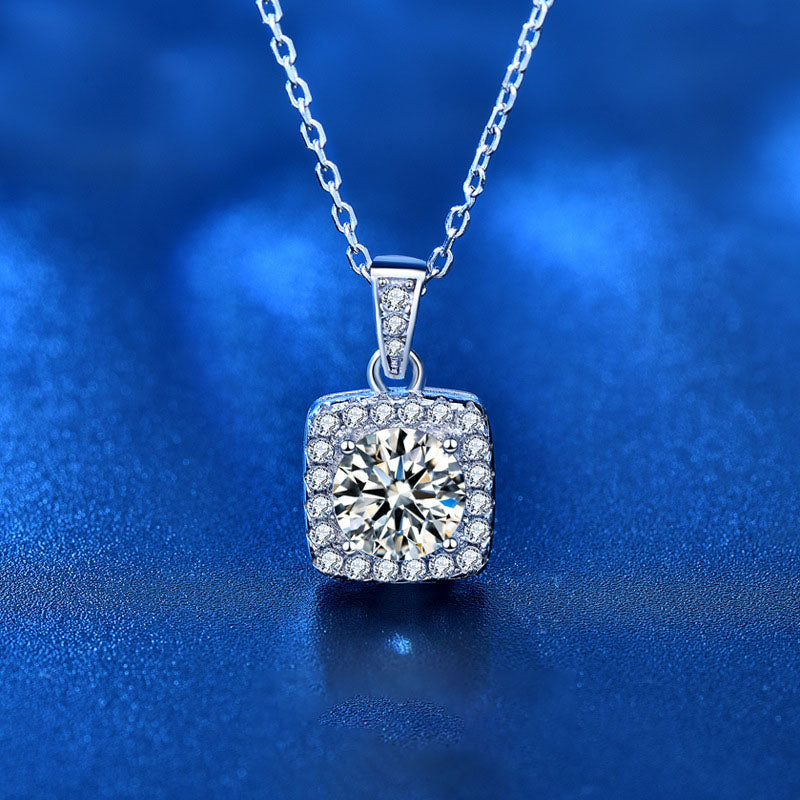 Close-up of 1 carat moissanite square halo pendant in sterling silver on blue background.