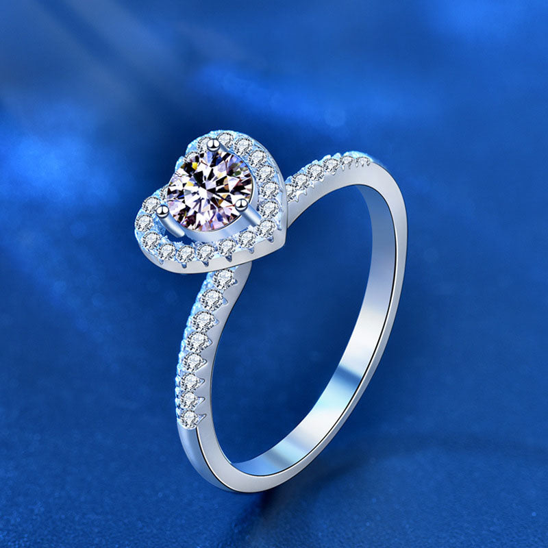 Angled view of heart-halo moissanite engagement ring in rhodium-plated 925 sterling silver with pavé CZ band.