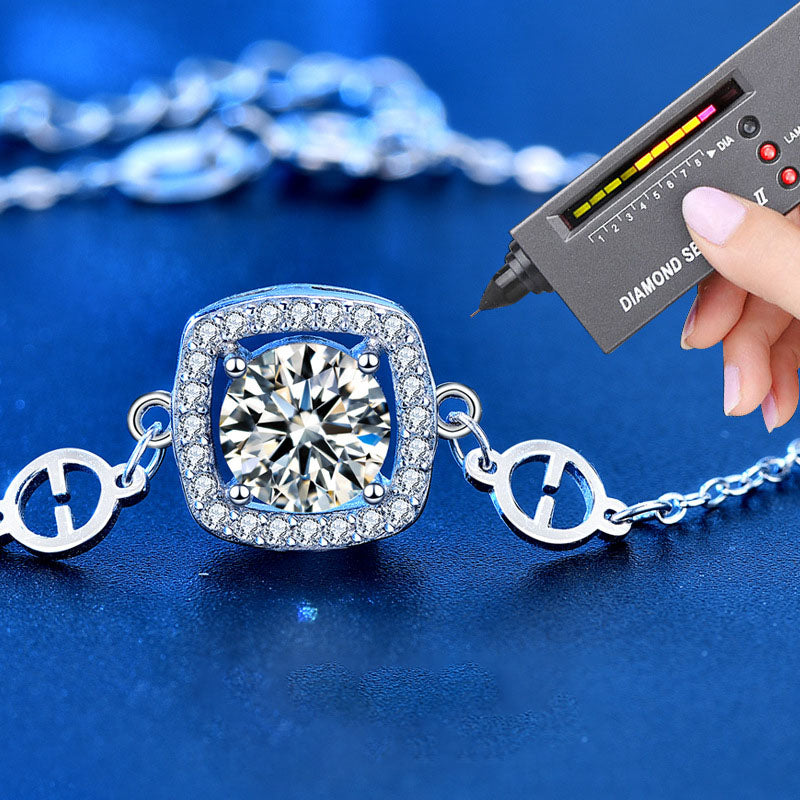Cushion halo moissanite bracelet in sterling silver being checked with a diamond tester.