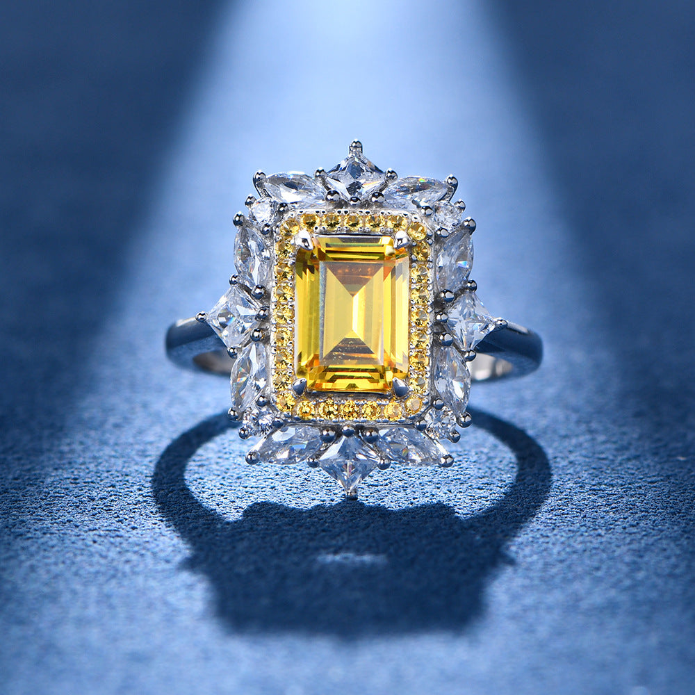 Close-up of yellow baguette-cut CZ halo flower ring in sterling silver on a blue backdrop.