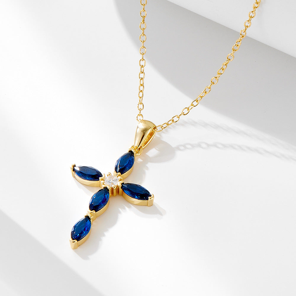 Gold-tone sterling silver necklace with blue marquise CZ stones in a cross shape on a white background
