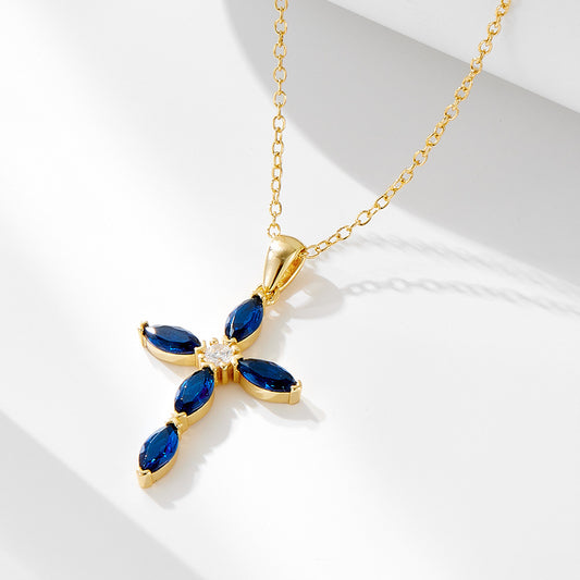 Gold-tone sterling silver necklace with blue marquise CZ stones in a cross shape on a white background