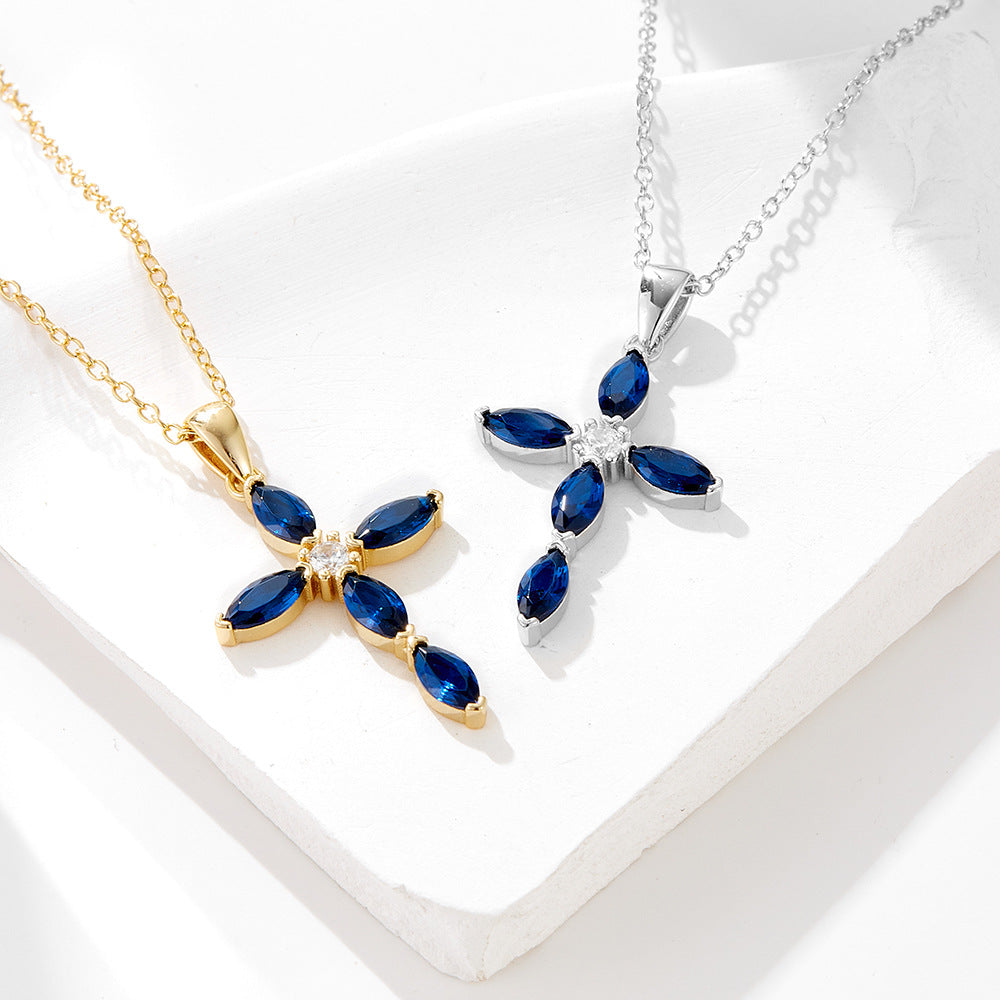 Gold and silver cross necklaces with blue stones side by side on a white display surface