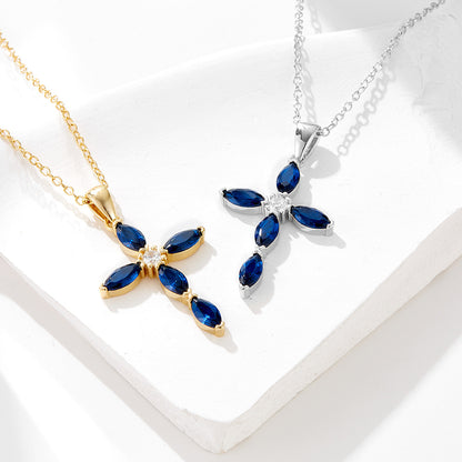 Gold and silver cross necklaces with blue stones side by side on a white display surface