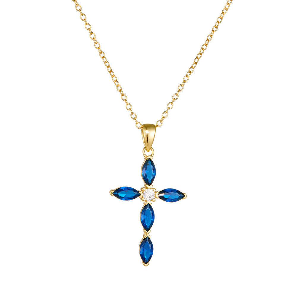 Close-up of gold blue CZ cross necklace on white background showing full pendant detail
