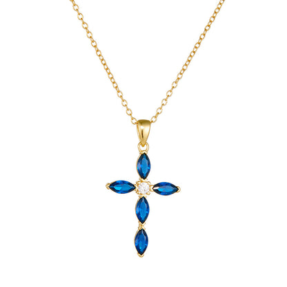 Close-up of gold blue CZ cross necklace on white background showing full pendant detail