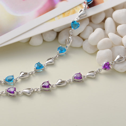 Two sterling-silver heart-link bracelets with blue and purple heart CZ stones side by side