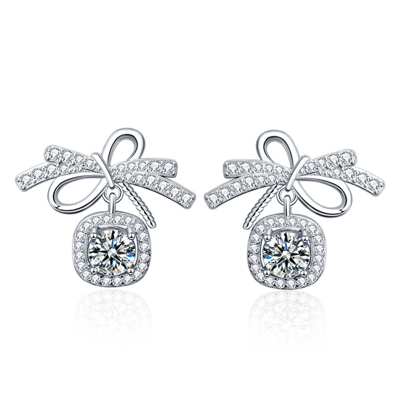 Packshot on white: bow stud earrings in rhodium-plated 925 silver with 0.5-carat moissanite and AAA CZ halos.