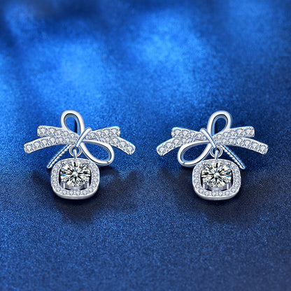 Angled view of ribbon-bow 0.5-carat moissanite stud earrings with AAA CZ pavé and cushion halo.