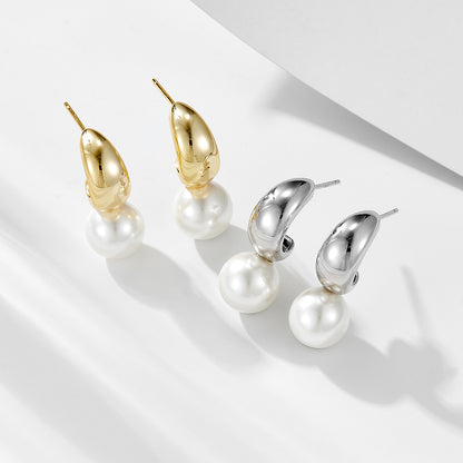 Gold and silver C-hoop created pearl dangle earrings set on white.