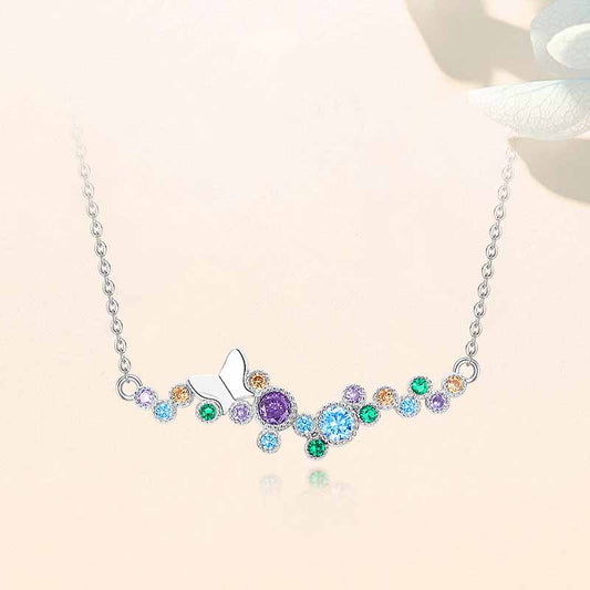Sterling silver butterfly bar necklace with rainbow CZ stones on a soft beige background.