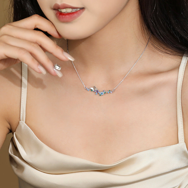 Model wearing sterling silver butterfly bar necklace with rainbow CZ stones at the collarbone