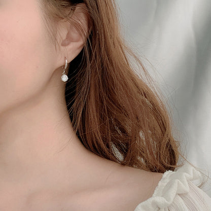 Model wearing elegant moissanite dangle earring in rhodium-plated sterling silver