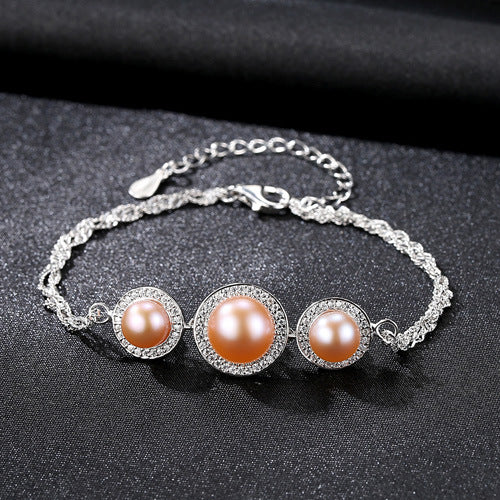 Sterling-silver bracelet with pink cultured pearls and CZ halos on black fabric.