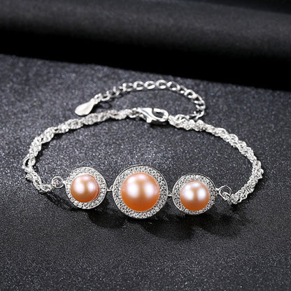 Sterling-silver bracelet with pink cultured pearls and CZ halos on black fabric.