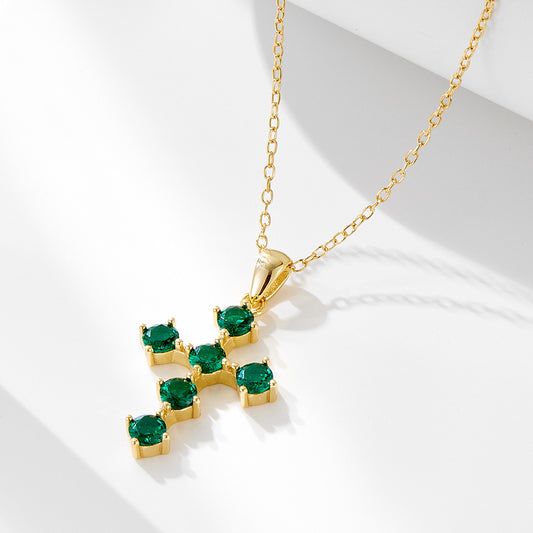 Gold-plated sterling silver cross necklace with green CZ stones on white background