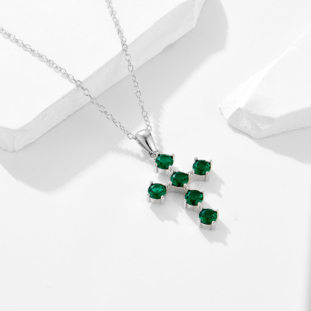 Rhodium-plated sterling silver cross necklace with green CZ stones on white background