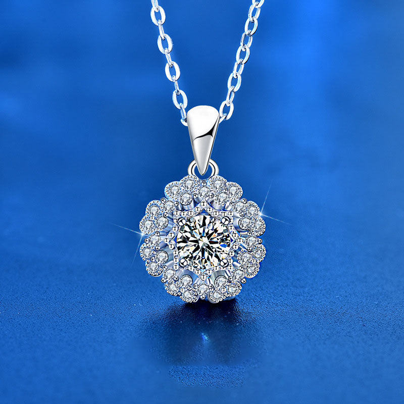 Front view of Moissanite flower pendant necklace on silver chain against blue background