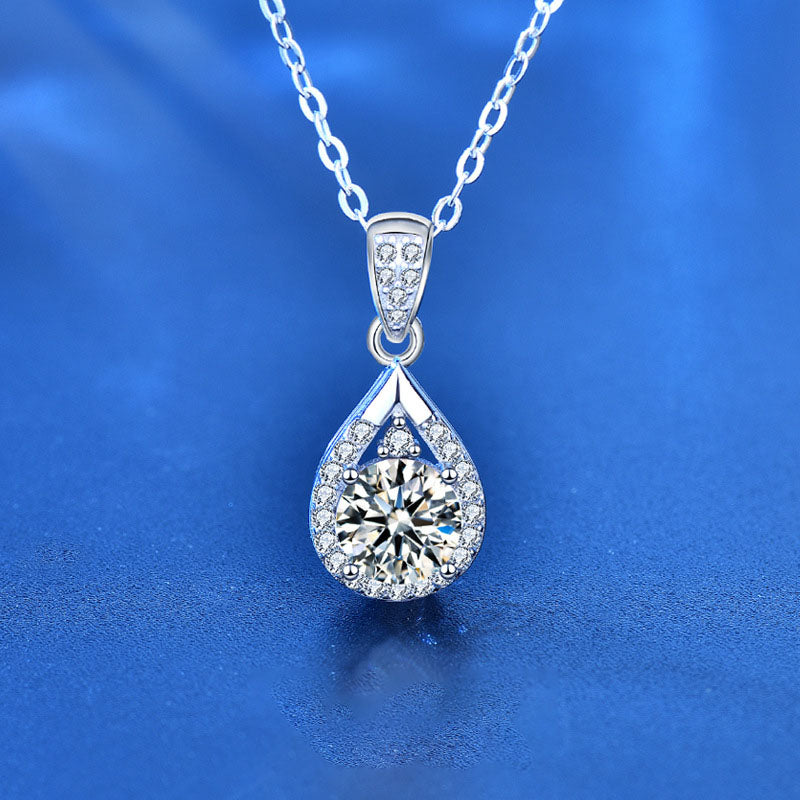 Close-up front view of a moissanite waterdrop pendant necklace in sterling silver on blue background.