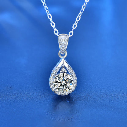 Close-up front view of a moissanite waterdrop pendant necklace in sterling silver on blue background.