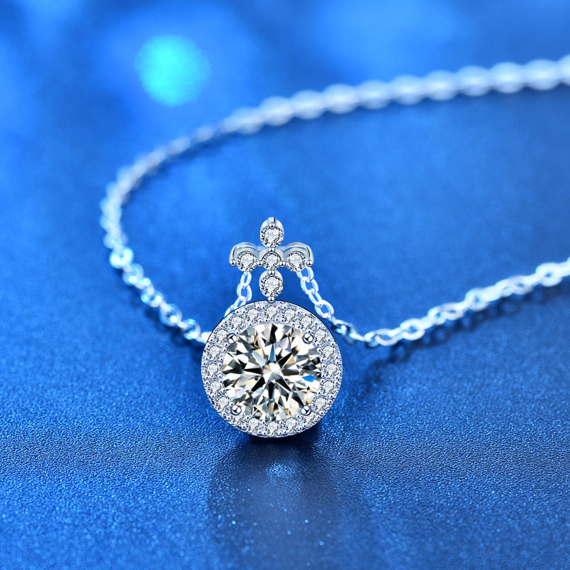 Angled view of the moissanite halo pendant and chain resting on a blue surface.