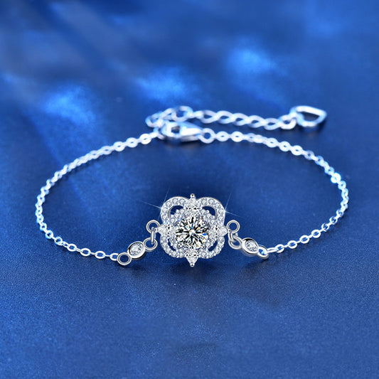 Close-up of sterling-silver four-leaf clover bracelet with moissanite and CZ stones on blue background