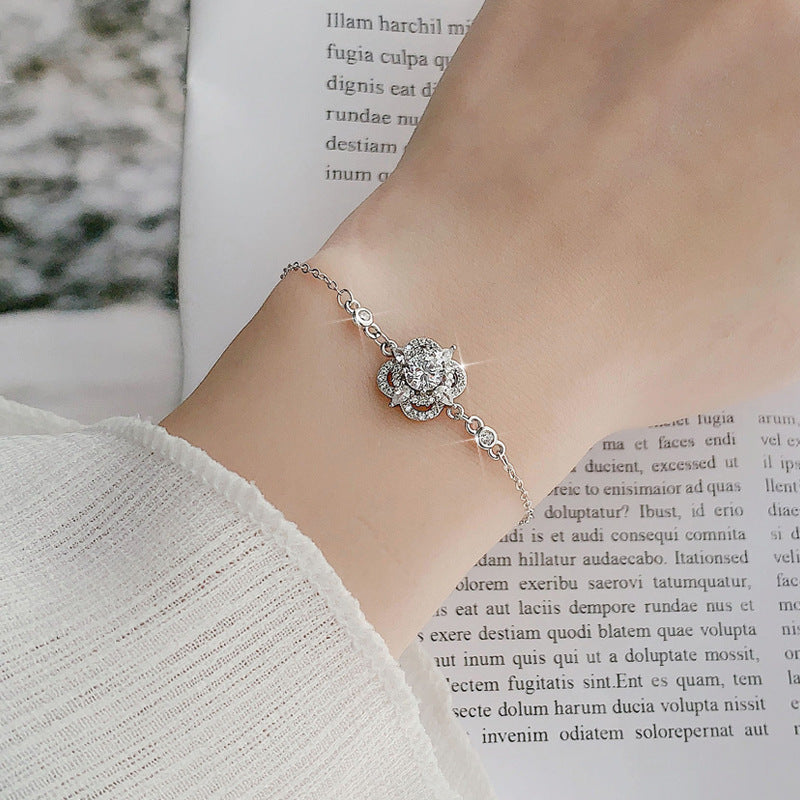 Woman wearing sterling-silver four-leaf clover bracelet with sparkling moissanite centerpiece
