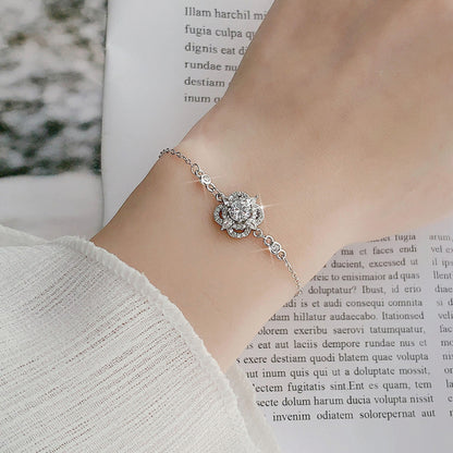 Woman wearing sterling-silver four-leaf clover bracelet with sparkling moissanite centerpiece