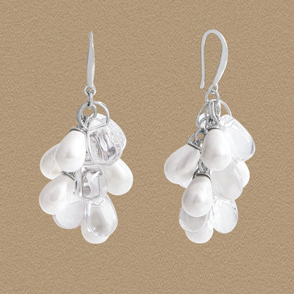 Front view of grape-cluster dangle earrings with white shell pearls and clear droplets in 925 silver on a beige background.