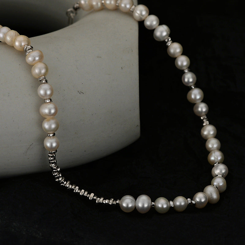 Detail view of irregular pearls and sterling-silver spacer beads on a dark background