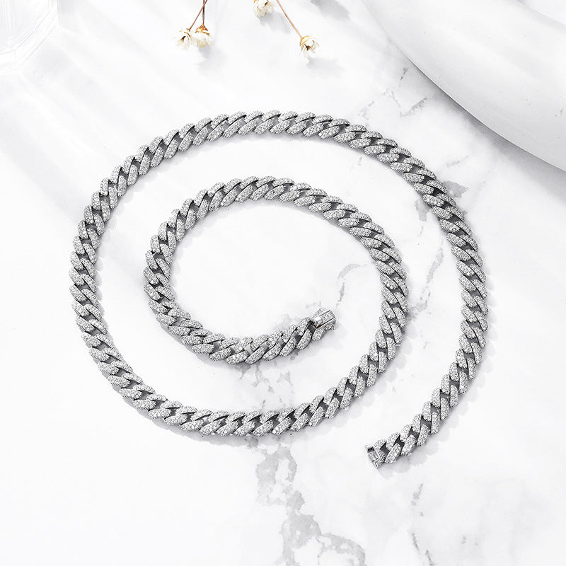 Spiral of silver iced CZ curb chain necklace on marble surface