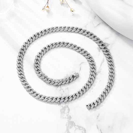 Spiral of silver iced CZ curb chain necklace on marble surface