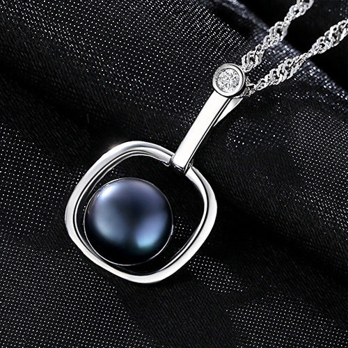 Artistic display of a black freshwater pearl necklace on silky black background