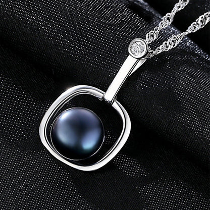 Artistic display of a black freshwater pearl necklace on silky black background