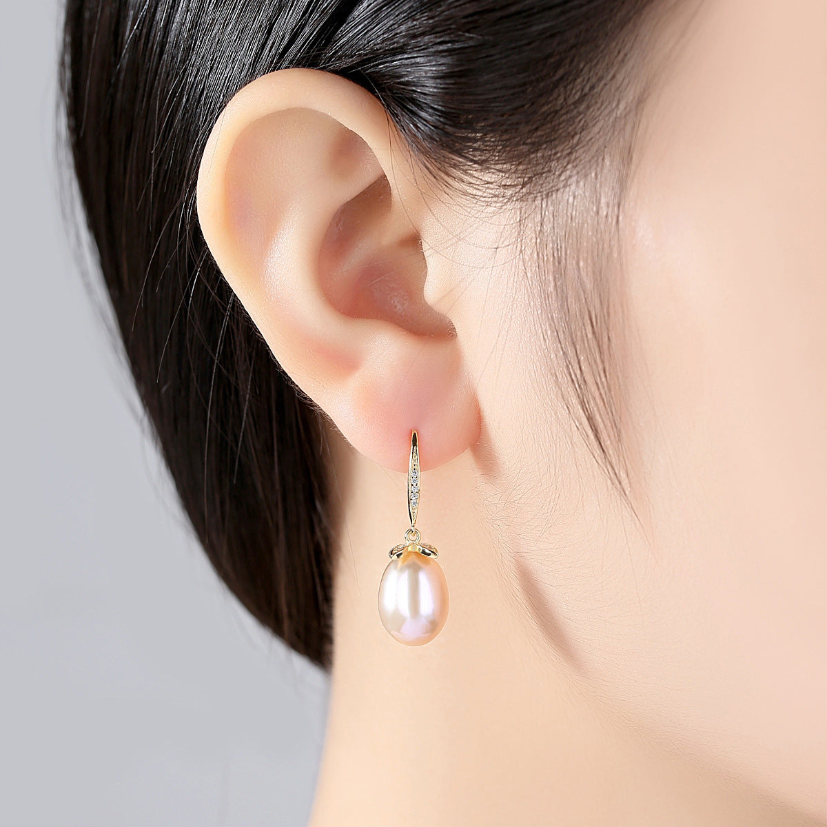 Model wearing natural pearl leaf dangle earring in a gold-finish variant.